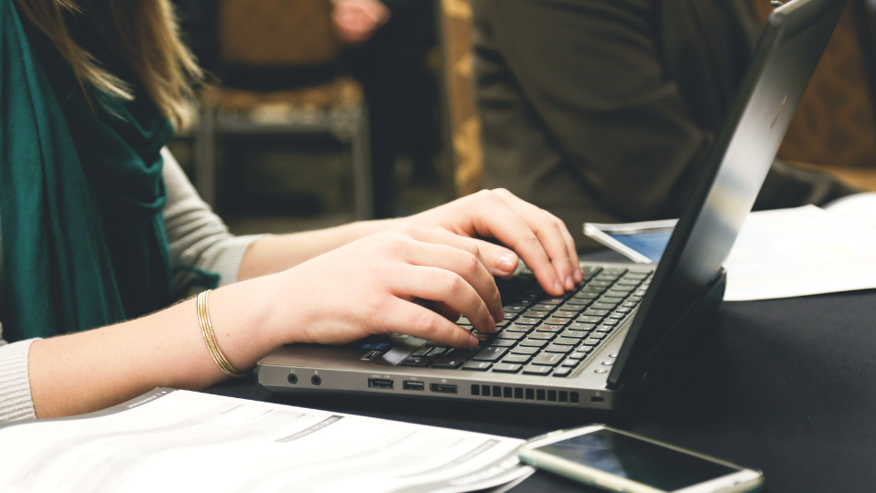 Close up view of a pair of hands typing n a laptop.