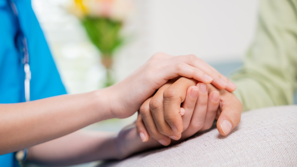 A pair of hands are wrapped around and holding a hand in an act of support.