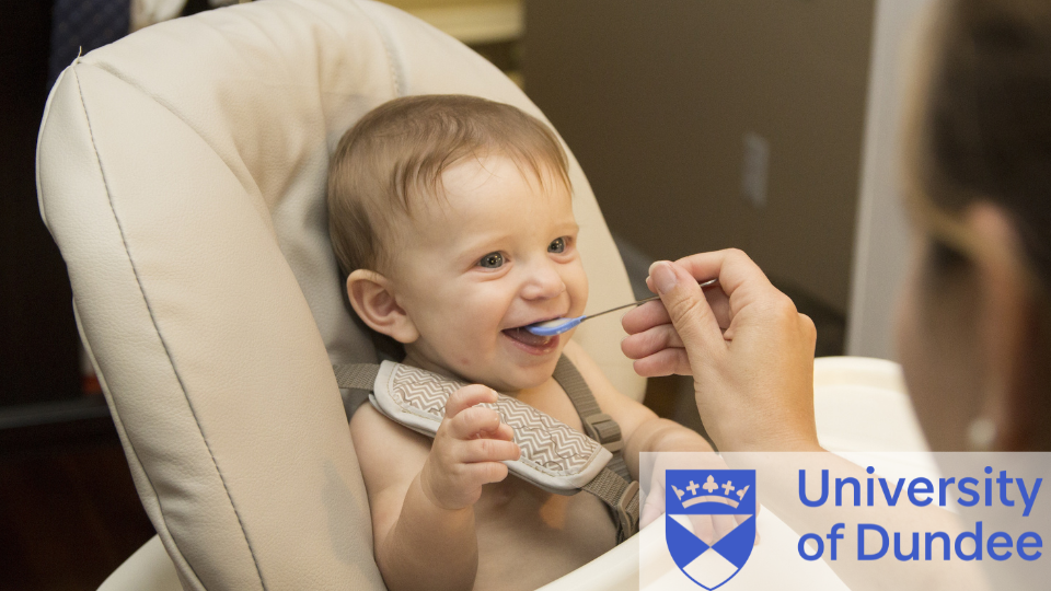 Baby in a feeding chair, someone from off camera is feeding the baby. University of Dundee logo is on the bottom right.