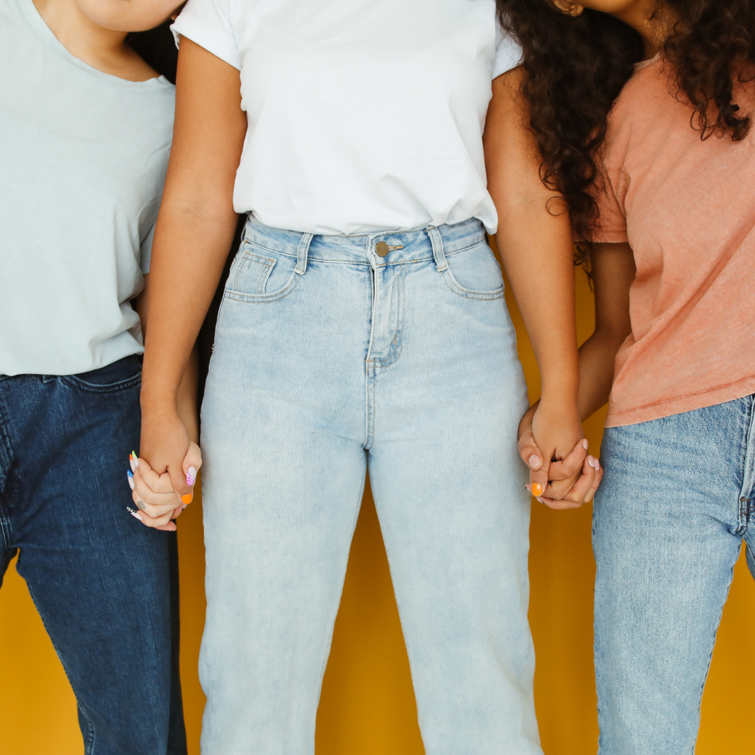 Picture showing only the torsos of young people in jeans and t shirts, holding hands against a yellow background.