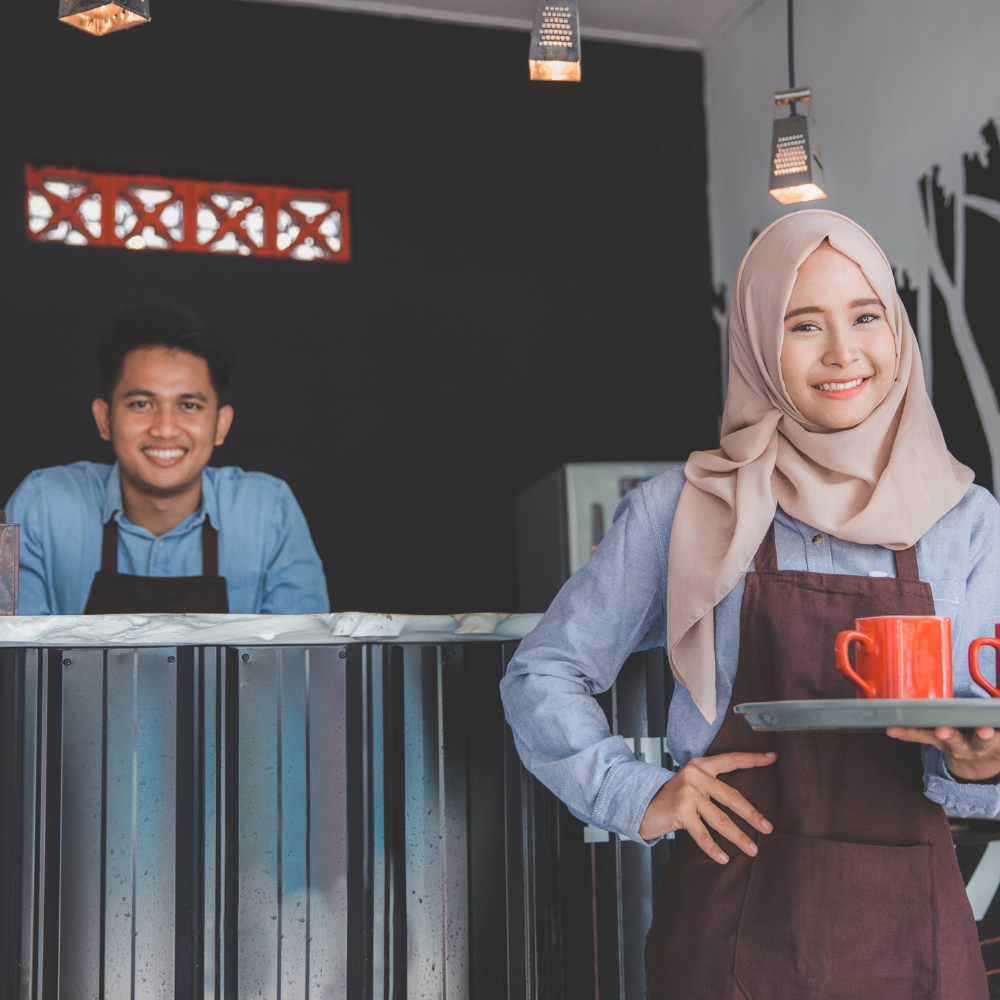 Cafe owner behind counter with waitress in a hijab
